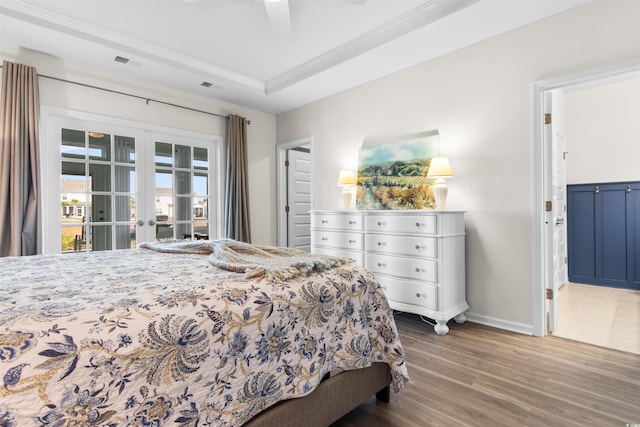 bedroom with wood-type flooring, french doors, a raised ceiling, ceiling fan, and crown molding