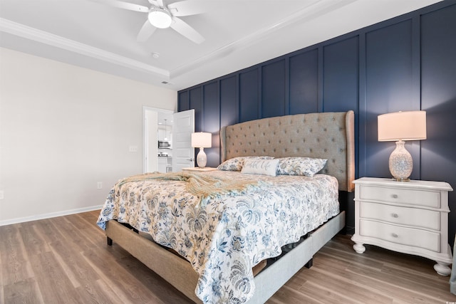 bedroom featuring crown molding, hardwood / wood-style floors, a tray ceiling, and ceiling fan