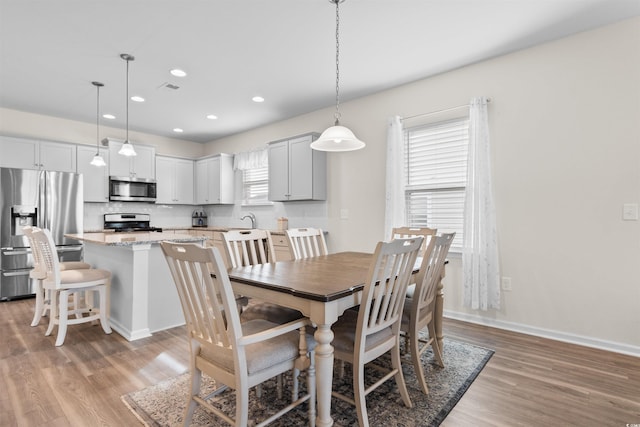 dining room with sink, plenty of natural light, and light hardwood / wood-style floors