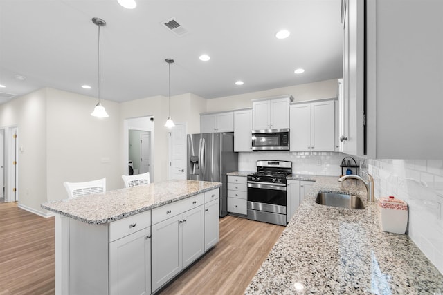 kitchen featuring appliances with stainless steel finishes, sink, decorative light fixtures, white cabinets, and decorative backsplash