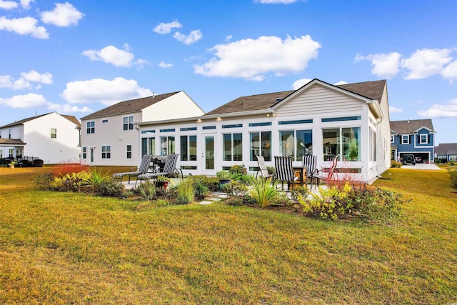 back of property with a sunroom and a yard