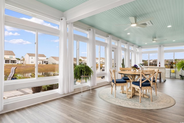 sunroom with ceiling fan, a water view, beamed ceiling, and a wealth of natural light