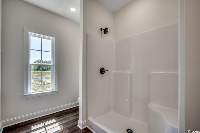 bathroom with baseboards, walk in shower, wood finished floors, and toilet