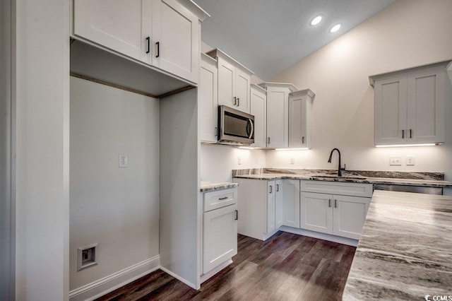 kitchen with recessed lighting, dark wood-style floors, a sink, stainless steel microwave, and light stone countertops