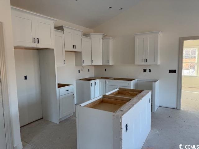 kitchen featuring lofted ceiling, white cabinets, and a center island