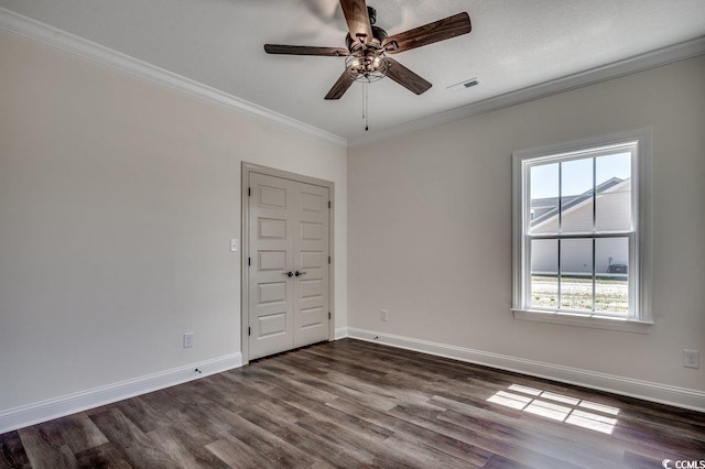 empty room with dark wood-style flooring, ceiling fan, baseboards, ornamental molding, and visible vents