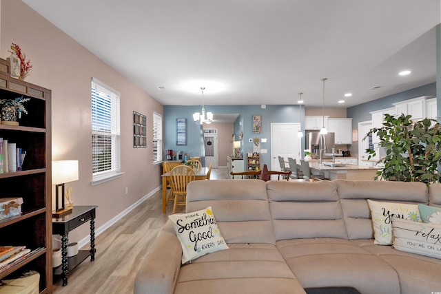 living room with light hardwood / wood-style floors and an inviting chandelier