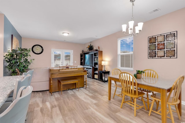 dining area featuring light wood-type flooring and a notable chandelier