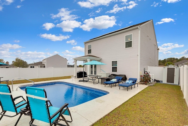 view of pool featuring a lawn, a storage shed, and a patio