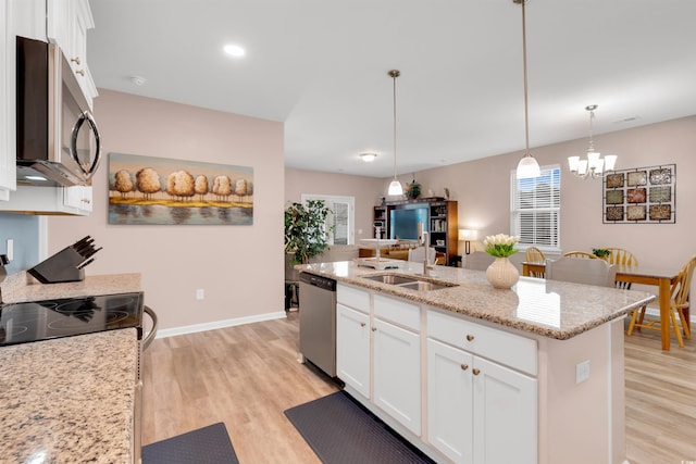 kitchen with white cabinets, light hardwood / wood-style flooring, an island with sink, decorative light fixtures, and stainless steel appliances