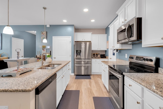 kitchen with pendant lighting, sink, white cabinets, and stainless steel appliances