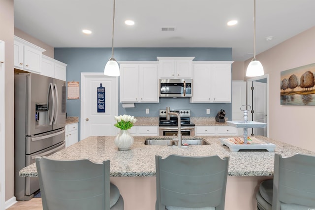 kitchen featuring white cabinets, appliances with stainless steel finishes, pendant lighting, and sink