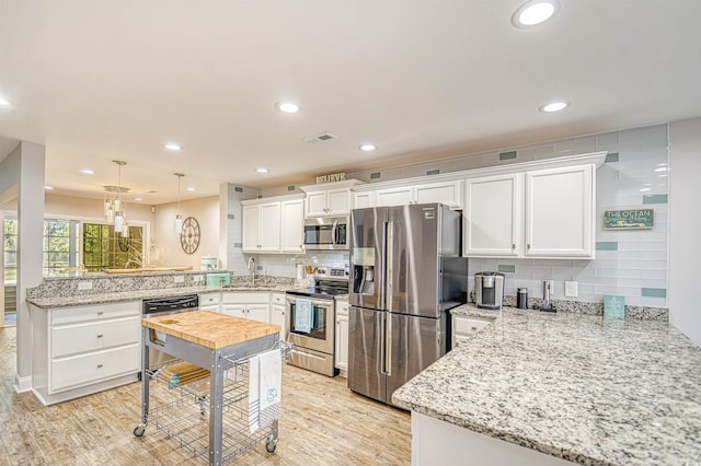 kitchen featuring white cabinetry, kitchen peninsula, and stainless steel appliances