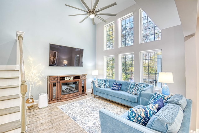 living room with ceiling fan, hardwood / wood-style floors, and a towering ceiling