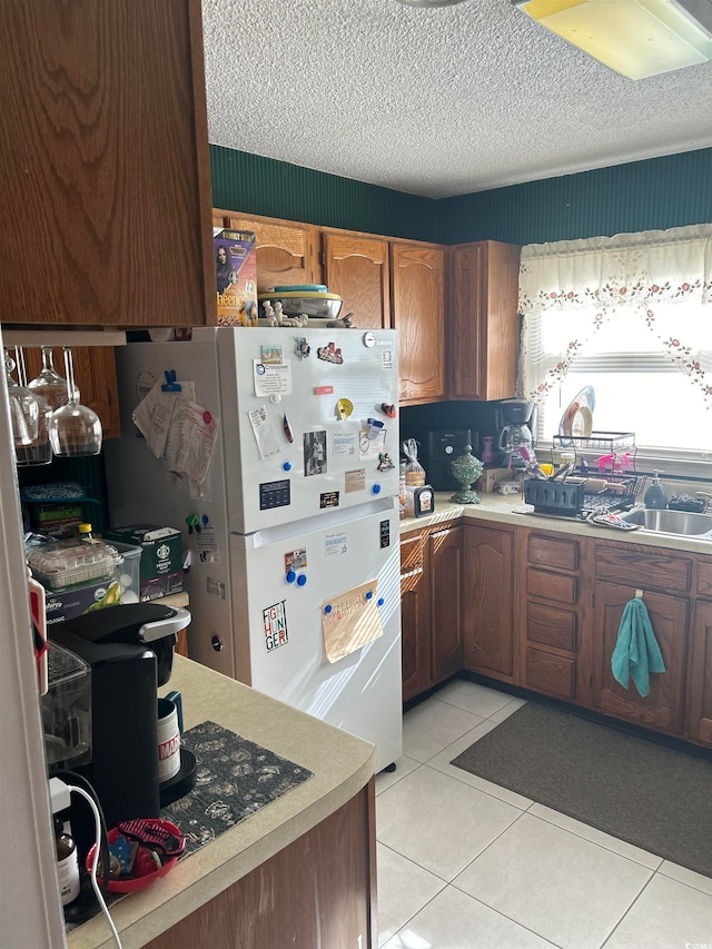 kitchen featuring light tile patterned flooring, white fridge, and a textured ceiling