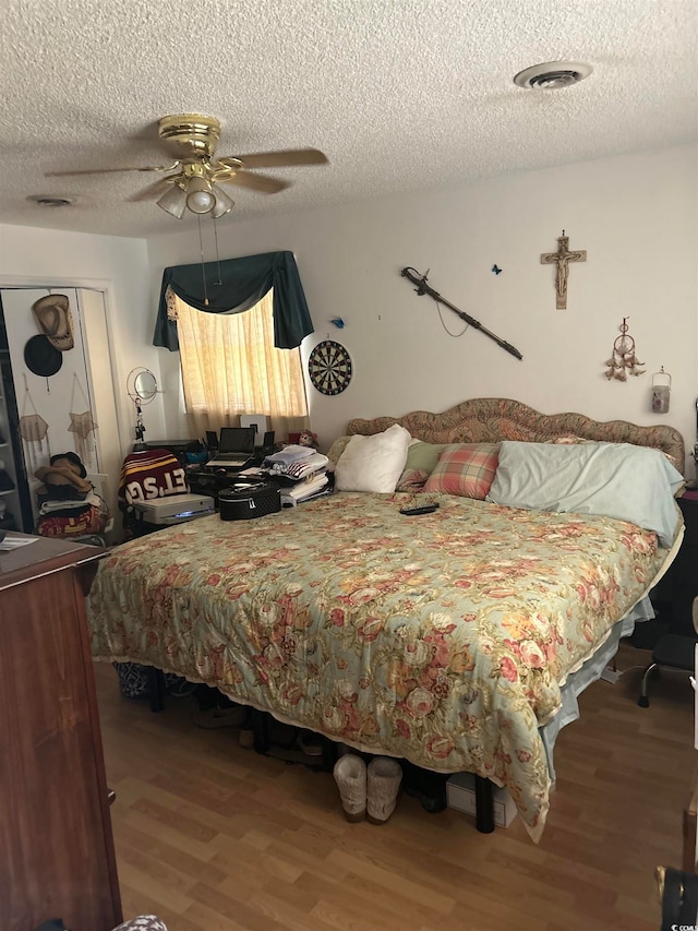 bedroom featuring ceiling fan, wood-type flooring, and a textured ceiling