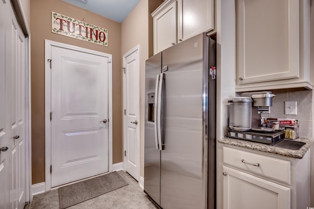 kitchen featuring stainless steel refrigerator with ice dispenser, light tile patterned floors, light stone countertops, decorative backsplash, and white cabinets