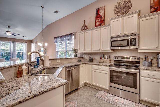 kitchen with vaulted ceiling, sink, hanging light fixtures, light stone counters, and stainless steel appliances