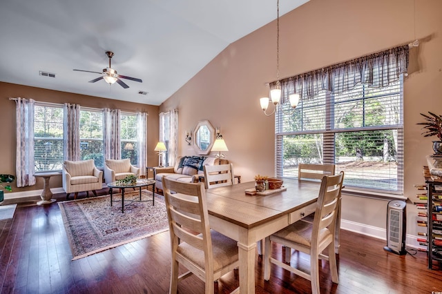 dining area with ceiling fan with notable chandelier, dark hardwood / wood-style floors, and vaulted ceiling