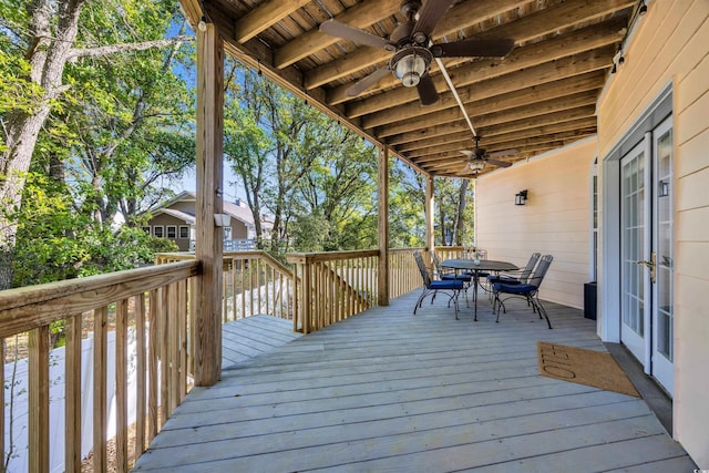 wooden terrace with outdoor dining area, a ceiling fan, and french doors