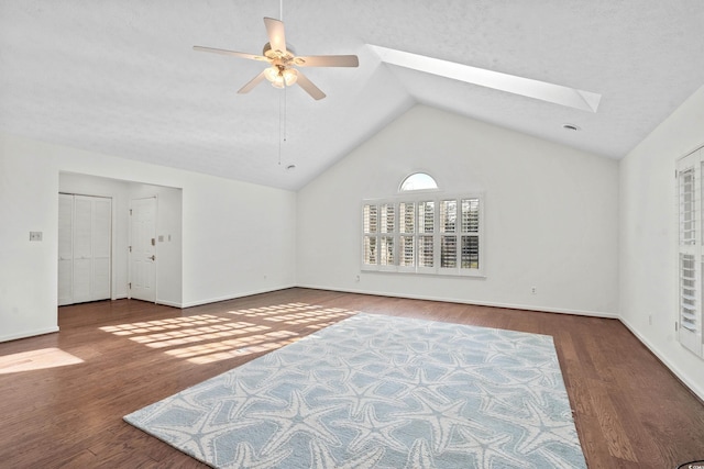 interior space featuring ceiling fan, vaulted ceiling with skylight, hardwood / wood-style floors, and a textured ceiling