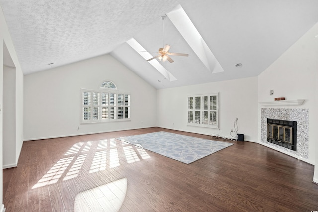 unfurnished living room featuring a tile fireplace, a skylight, wood-type flooring, ceiling fan, and a textured ceiling