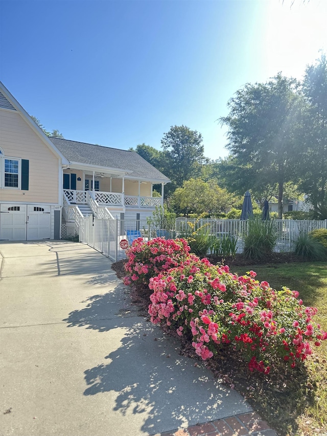 view of property exterior featuring a porch, fence, driveway, a garage, and stairway
