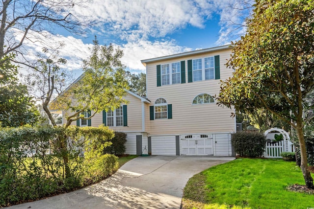view of front facade with concrete driveway, a front lawn, an attached garage, and fence