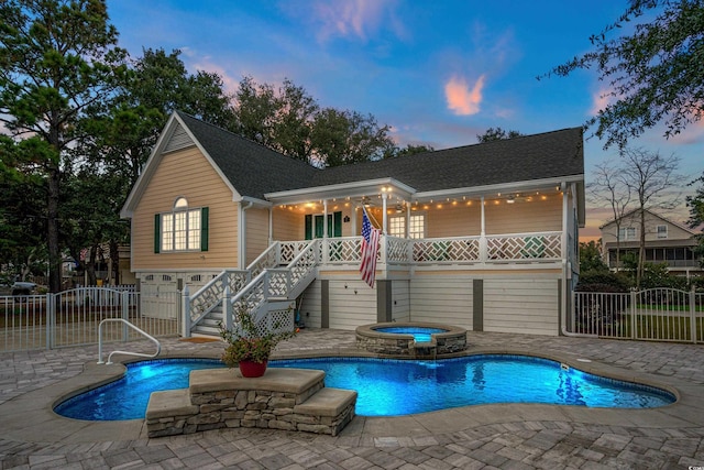 pool at dusk featuring a patio area and an in ground hot tub