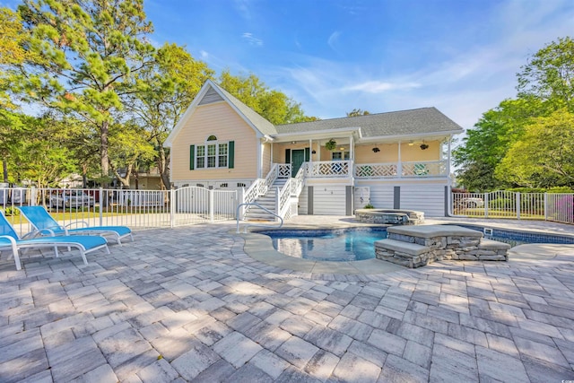 back of property featuring a hot tub, fence, a fenced in pool, and stairs