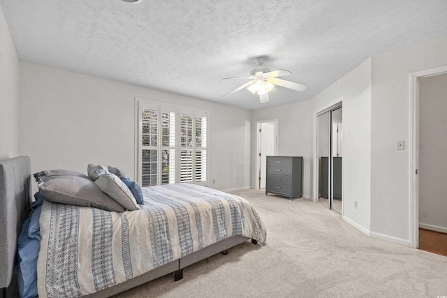 carpeted bedroom featuring ceiling fan, a textured ceiling, and a closet