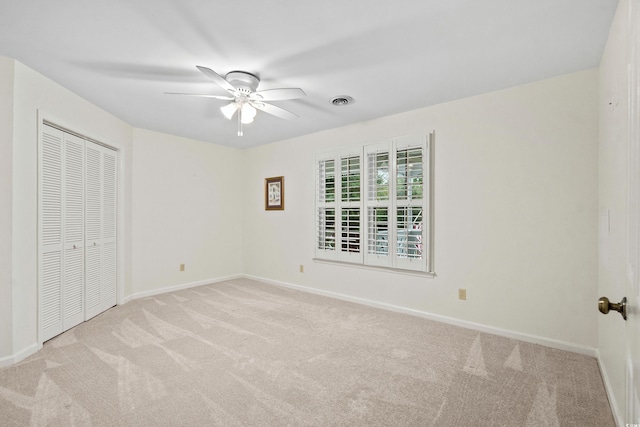 unfurnished bedroom with ceiling fan, a closet, and light carpet