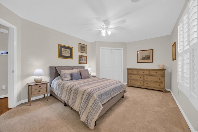 bedroom featuring light carpet, a closet, baseboards, and a ceiling fan