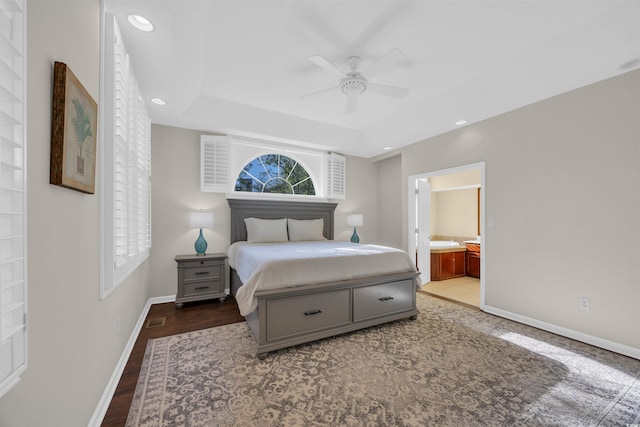 bedroom with a tray ceiling, ensuite bathroom, baseboards, and recessed lighting