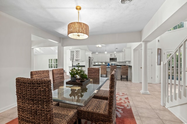 tiled dining space with decorative columns, sink, and a textured ceiling