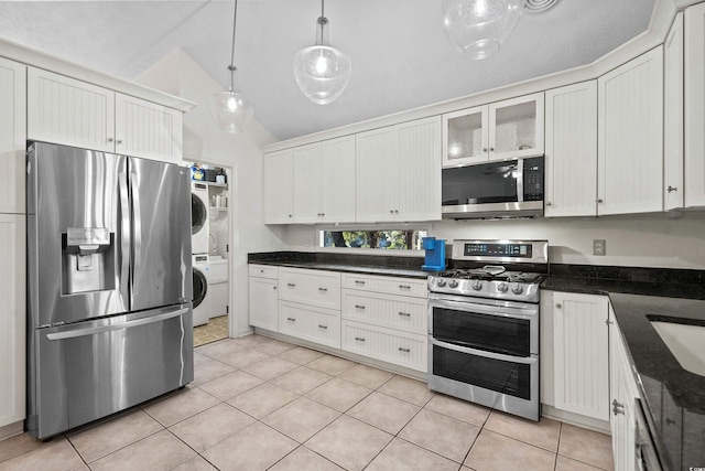 kitchen with stainless steel appliances, light tile patterned flooring, stacked washer / drying machine, white cabinets, and hanging light fixtures