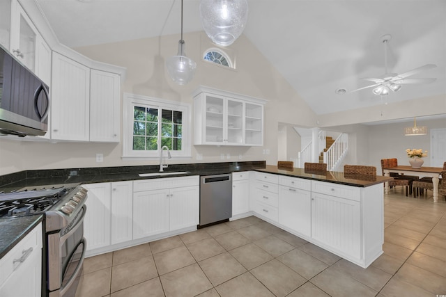 kitchen with light tile patterned flooring, a sink, high vaulted ceiling, white cabinets, and appliances with stainless steel finishes