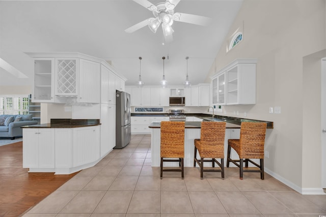 kitchen featuring a peninsula, stainless steel appliances, open shelves, high vaulted ceiling, and dark countertops