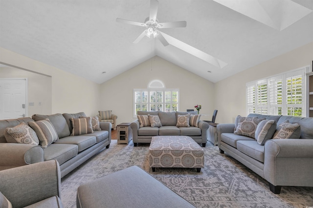 living room with lofted ceiling with skylight, a ceiling fan, and plenty of natural light