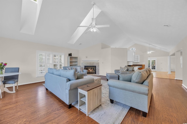 living room featuring light wood-style flooring, a glass covered fireplace, ceiling fan, and high vaulted ceiling