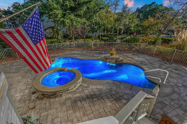 pool at dusk with an in ground hot tub and a patio