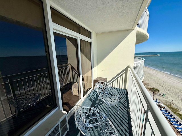 balcony featuring a water view and a view of the beach