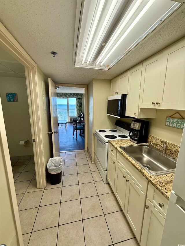 kitchen with white cabinetry, sink, light tile patterned floors, and white electric stove