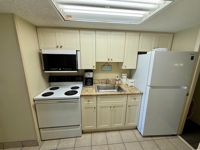 kitchen with a textured ceiling, white appliances, sink, white cabinetry, and light tile patterned flooring