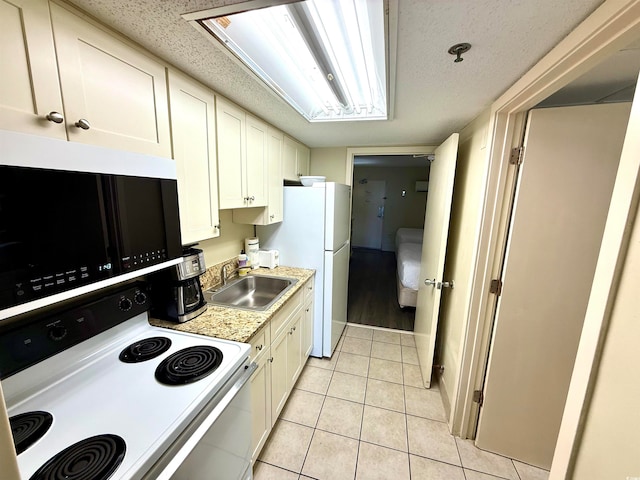 kitchen with light stone countertops, white appliances, sink, white cabinetry, and light tile patterned flooring