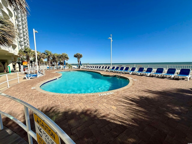 view of pool with a patio area and a water view