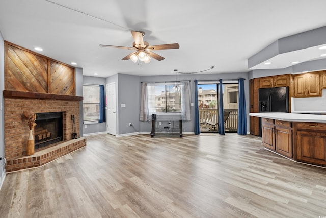 unfurnished living room featuring a brick fireplace, ceiling fan, and light hardwood / wood-style flooring