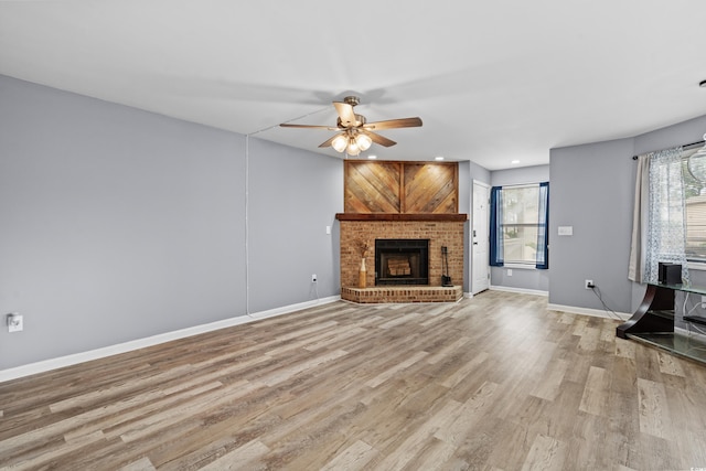 unfurnished living room featuring a fireplace, ceiling fan, and light hardwood / wood-style flooring