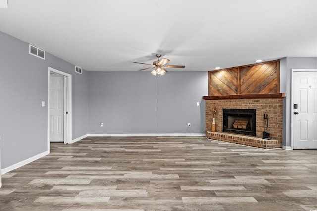 unfurnished living room featuring light hardwood / wood-style floors, a brick fireplace, and ceiling fan