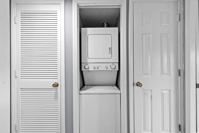 clothes washing area featuring stacked washing maching and dryer